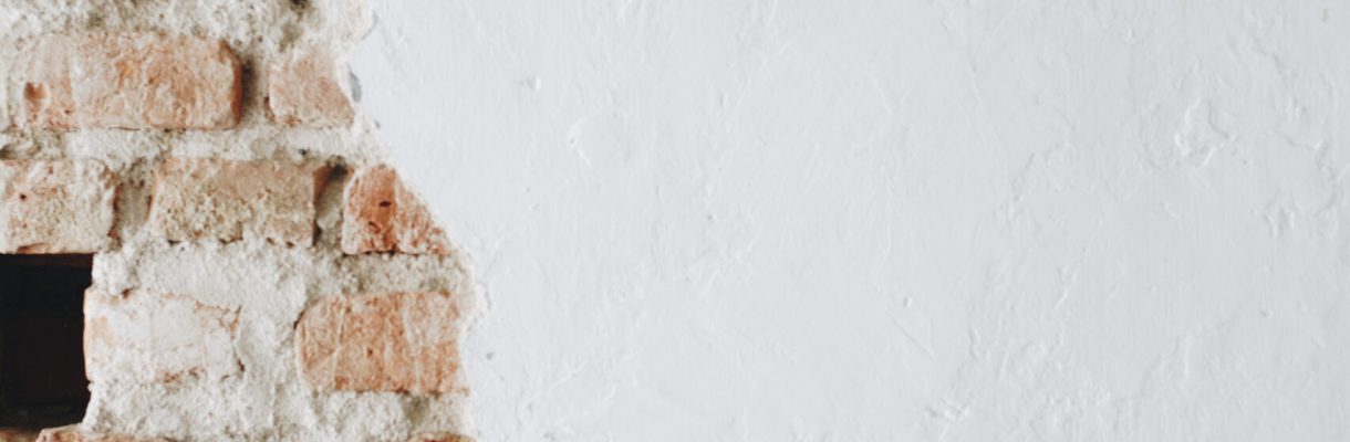 A cracked concrete white wall with bricks A cracked concrete white wall with bricks